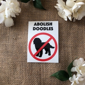 Peut inclure: Un autocollant blanc avec un cercle rouge et une silhouette noire d'un chien doodle avec une ligne rouge qui le traverse. Le texte "ABOLISH DOODLES" est imprimé en noir au-dessus du cercle.