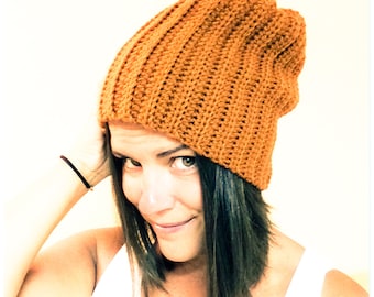 May include: A woman wearing a brown crocheted beanie hat. The hat has a slouchy fit and is made with a textured stitch.