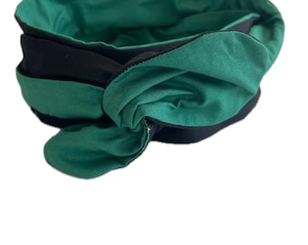 May include: A black and green fabric headband with a knotted design. The headband is reversible, with a solid green interior and a black exterior. The knot detail adds a stylish touch to this hair accessory.
