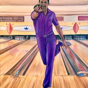 Jesus Quintana wearing his purple bowling suit with purple shoes is pointing with his right hand and one leg kicked up behind him. He has a big smile on his face after he bowled a strike. classic bowling alley behind him with pins and lanes.