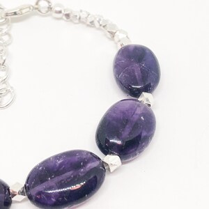 May include: A silver chain bracelet with three oval-shaped amethyst beads.
