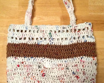 May include: A white crocheted tote bag with brown crocheted trim. The bag is made from recycled plastic bags.