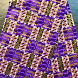 Puede incluir: Una tela doblada con un patr&oacute;n geom&eacute;trico en tonos morado, dorado, negro y blanco. El dise&ntilde;o presenta formas repetidas, incluyendo tri&aacute;ngulos y rect&aacute;ngulos, creando una apariencia compleja y texturizada. La tela parece nueva y sin usar.