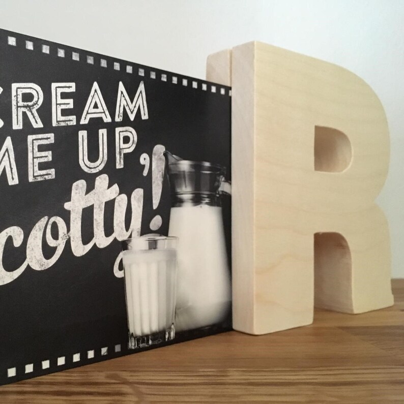 May include: Black chalkboard sign with white text that reads "Cream Me Up, Scotty!" with a pitcher of milk and a glass of milk in front of it. A wooden letter "R" is to the right of the sign.