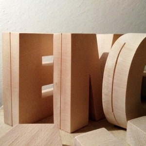 May include: Wooden letters spelling out the word "ENG" in a light brown color. The letters are freestanding and have a simple, modern design.