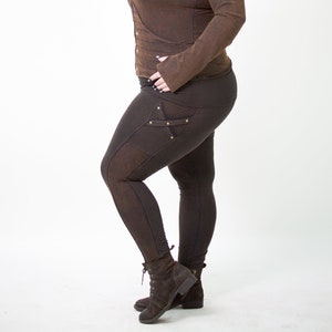 May include: A brown hooded jacket with a zip fastening and a brown pair of leggings with decorative stitching and gold accents. The model is wearing brown boots.
