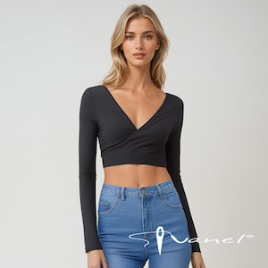 May include: A black long-sleeved wrap crop top with a deep V-neckline. The top is made of a soft, stretchy fabric and has a fitted silhouette. The model is wearing the top with blue jeans.