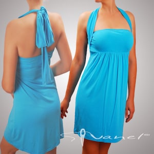 May include: A turquoise halter dress with a gathered waist and a flowing skirt. The dress features a tie closure at the back of the neck. The fabric appears soft and lightweight, suitable for warm weather. The dress is shown on a person.