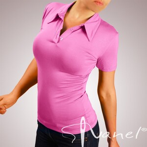 May include: A pink short-sleeved collared shirt with a button closure. The shirt is fitted and has a slightly gathered look in the front.