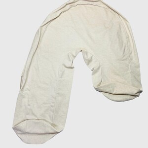 May include: A beige pregnancy pillow shaped like a crescent moon. The pillow is made of a soft, comfortable fabric and is designed to provide support for the back, belly, and legs during pregnancy.