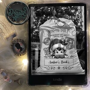 Può includere: Immagine in bianco e nero di un e-reader Kindle che mostra un sacco di Natale personalizzato con un elfo che spunta fuori. Il sacco riporta la scritta "Polo Nord Servizio notturno Speciale per: Certificato" e "Il libro di Amber".