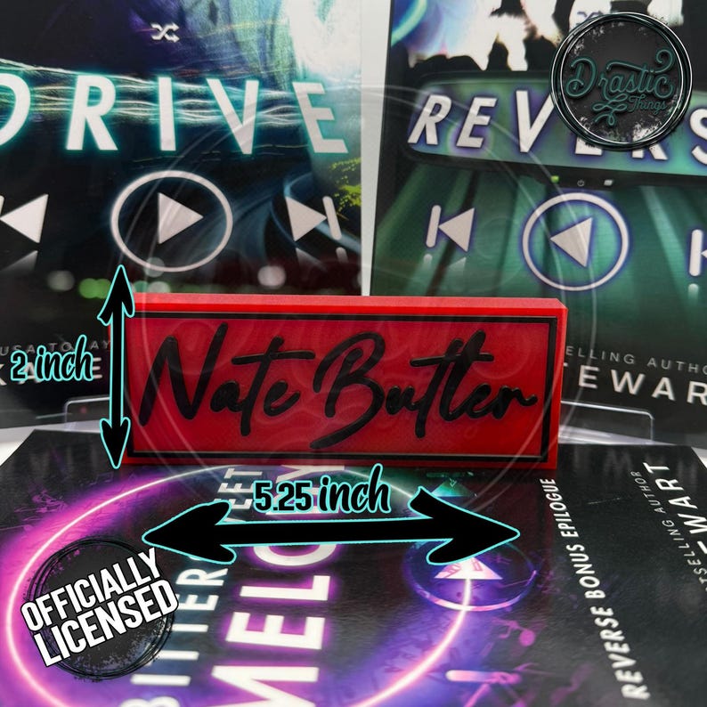May include: A red rectangular sign with the name "Nate Butter" in black script, measuring 5.25 inches long and 2 inches high. The sign is positioned in front of book covers. The words "Officially Licensed" are also visible.
