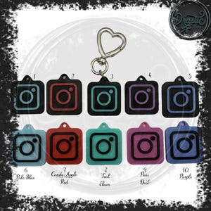 May include: A collection of ten Instagram-themed keychains in various colors, including pale blue, red, teal, and purple. Each keychain features a black square with a colored Instagram logo and a silver heart-shaped clasp.