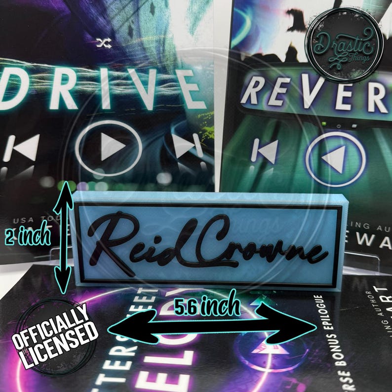 May include: A light blue rectangular sign with the name "Reid Crowne" in black script. The sign is 5.6 inches long and 2 inches tall. The background features book covers with the words "DRIVE" and "REVERSE". The sign is officially licensed.
