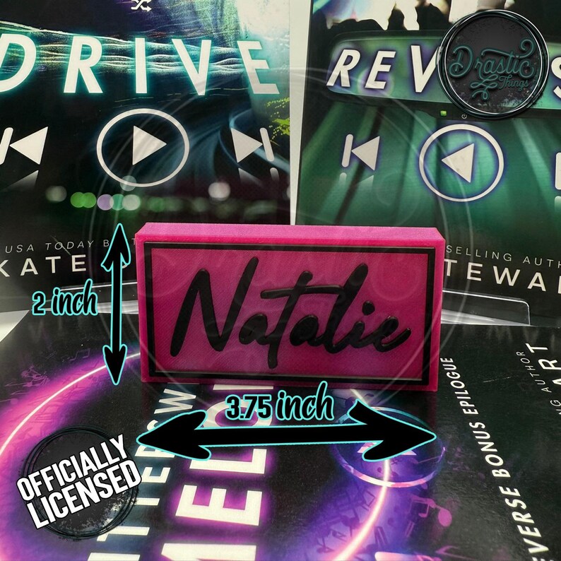 May include: A pink rectangular nameplate, 3.75 inches wide and 2 inches tall, with the name "Natalie" in black script. The nameplate is placed on top of a book with the word "DRIVE" visible. The words "OFFICIALLY LICENSED" are also visible.