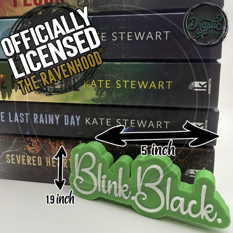 Op de afbeelding: Een stapel boeken met donkere covers, met titels van Kate Stewart. Een groen, gestileerd "Blink Black" bord staat op de voorgrond, met een lengte van ongeveer 12,7 cm en een hoogte van 4,8 cm. De boeken zijn officieel gelicenseerde "The Ravenhood" merchandise.