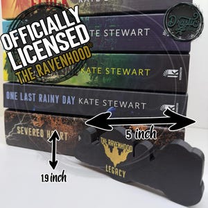 Op de afbeelding: Een stapel boeken met de titel "The Ravenhood" en een zwarte houten boekenstandaard van 12,7 cm lang. De boeken zijn van Kate Stewart, met titels als "Severed Hart" en "One Last Rainy Day". De standaard is voorzien van de tekst "The Ravenhood Legacy".