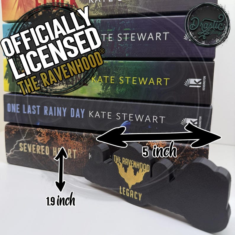 Op de afbeelding: Een stapel boeken met de titel "The Ravenhood" en een zwarte houten boekenstandaard van 12,7 cm lang. De boeken zijn van Kate Stewart, met titels als "Severed Hart" en "One Last Rainy Day". De standaard is voorzien van de tekst "The Ravenhood Legacy".
