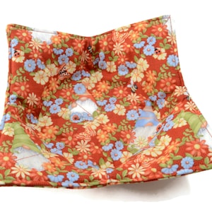 May include: Red and white quilted bowl cozy with a floral pattern and gnomes. The bowl cozy is perfect for keeping your bowls warm.