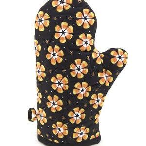 May include: Black oven mitt with a pattern of orange and white candy corn flowers.