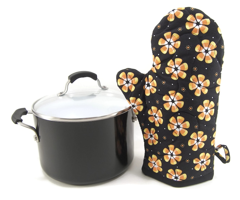 May include: Black pot with a lid and a black and orange candy corn patterned oven mitt.