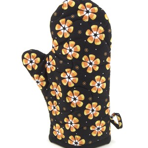 May include: Black oven mitt with a pattern of orange and white candy corn flowers.