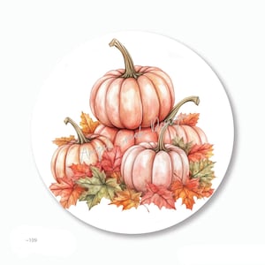 May include: A watercolor illustration of a stack of pumpkins in shades of peach and orange, surrounded by autumn leaves in red, orange, and green. The pumpkins have green stems and are set against a white background.