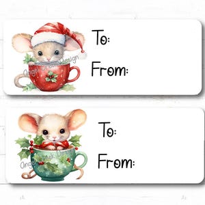 May include: Two printable gift tags featuring a cute cartoon mouse wearing a Santa hat and sitting in a mug. The top tag has a red mug with holly and the bottom tag has a green mug with holly. Both tags have the words "To:" and "From:" printed on them.