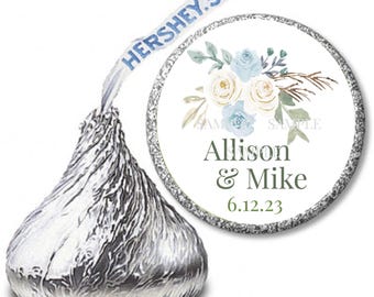 May include: White Hershey's Kisses chocolate candy wrappers with a round sticker featuring a watercolor floral design in shades of blue and green. The sticker says "Alison & Mike" and "6.12.23".