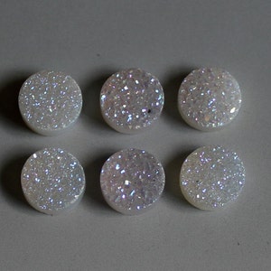 May include: Six white iridescent round cabochon gemstones with a sparkly finish.