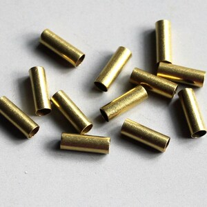 Puede incluir: Un grupo de 12 tubos de metal de color dorado, probablemente utilizados para la fabricaci&oacute;n de joyas o manualidades.