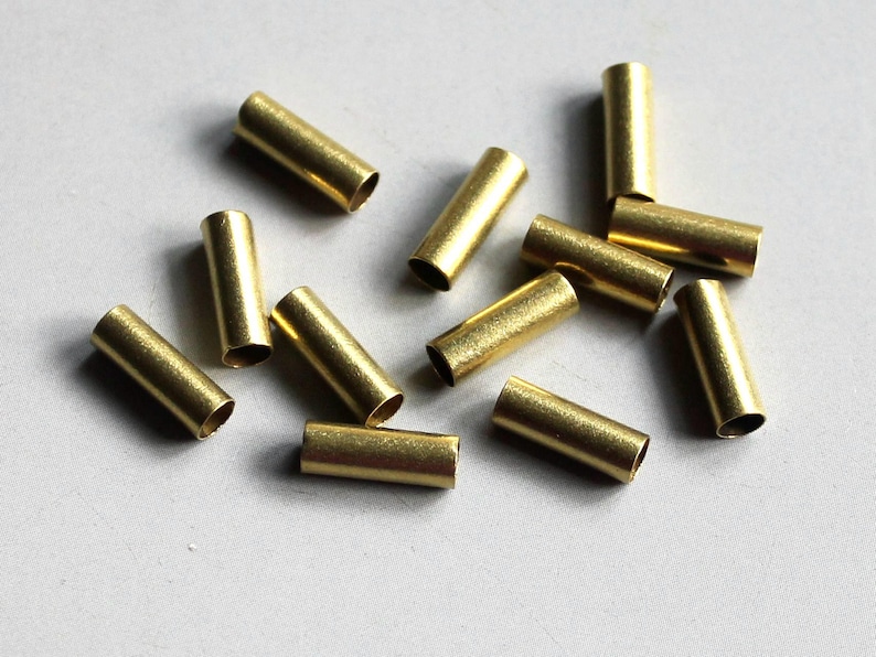 Puede incluir: Un grupo de 12 tubos de metal de color dorado, probablemente utilizados para la fabricaci&oacute;n de joyas o manualidades.