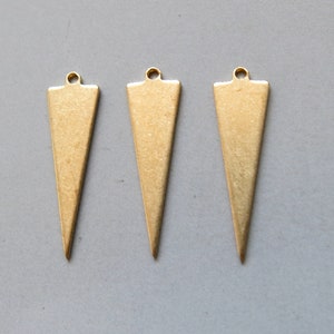 May include: Three gold-colored triangle-shaped metal charms with a hole at the top for attaching to jewelry or other crafts.