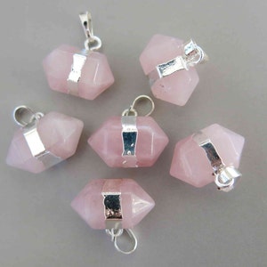 May include: Six rose quartz pendants with silver-colored metal accents. Each pendant has a hexagonal shape and a loop for a chain. The pendants are a soft pink color.