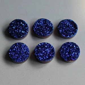 May include: Six round, blue, iridescent, sparkly, agate cabochons. The cabochons are approximately 1 inch in diameter.