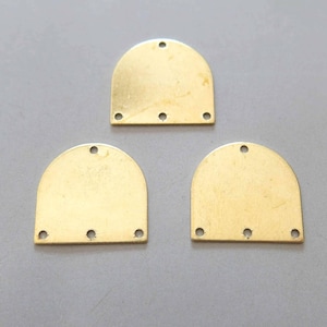 May include: Three gold-coloured metal arch-shaped pieces with rounded tops and four holes each. The pieces are arranged in a triangular formation.