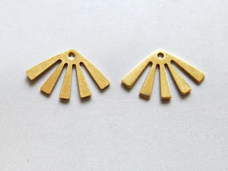 May include: Two gold metal sunburst charms with a hole at the top for attaching to jewellery or other crafts.
