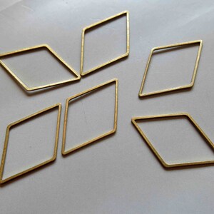 May include: Six gold-colored metal diamond-shaped hoops. The hoops are all the same size and shape, and they are arranged in a starburst pattern.