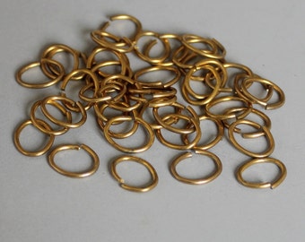 Puede incluir: Un montón de anillos de salto de metal de color dorado. Los anillos son de forma ovalada y tienen un acabado liso.