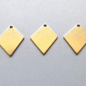 May include: Three gold-colored metal diamond-shaped charms with a small hole at the top for attaching to jewelry or other crafts.