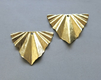 Può includere: Due decorazioni metalliche dorate a forma di triangolo con un design a ventaglio. Ogni decorazione ha un foro nella parte superiore.