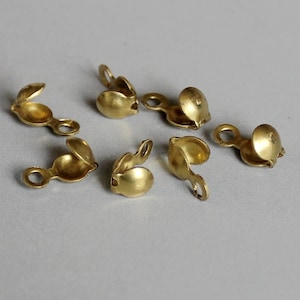 May include: Six gold-toned metal clasps with a small loop on each side. The clasps are designed to be used for jewelry making.