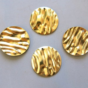 May include: Four gold-colored metal round discs with a textured surface and a hole in the center.