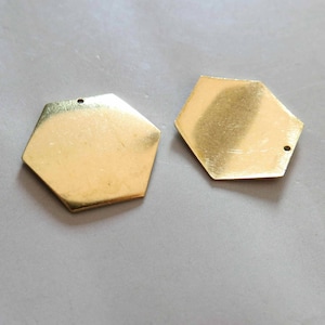 May include: Two gold-coloured hexagonal metal charms with a hole at the top.