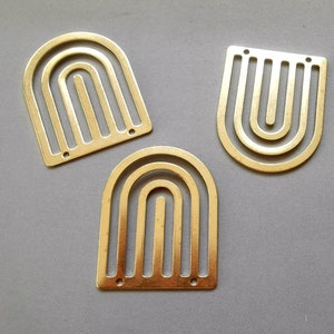 May include: Three gold metal arch shapes with a geometric design. The arches are all the same size and shape, but have different numbers of lines.
