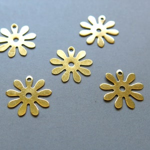 以下が含まれることがあります： 中央に穴が開いた金色の金属製のフラワーモチーフのチャームが5つ。チャームの直径は約2.5cmです。