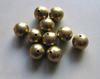 May include: A group of ten round, gold-colored metal beads with a hole in the center of each bead.