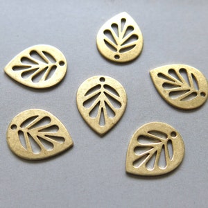 May include: Six gold-coloured metal leaf-shaped charms with a cut-out design. The charms are approximately 2.5 cm long and have a teardrop shape.