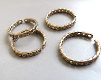 May include: Four gold-toned toe rings with a chain link design. The rings are stacked on top of each other.