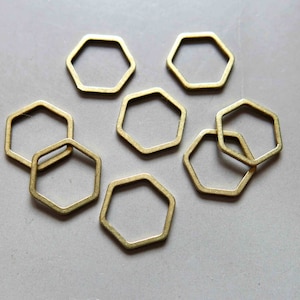 Könnte beinhalten: Ein Satz von acht goldfarbenen sechseckigen Metallringen. Die Ringe sind alle gleich groß und gleich geformt und in einem zufälligen Muster angeordnet.